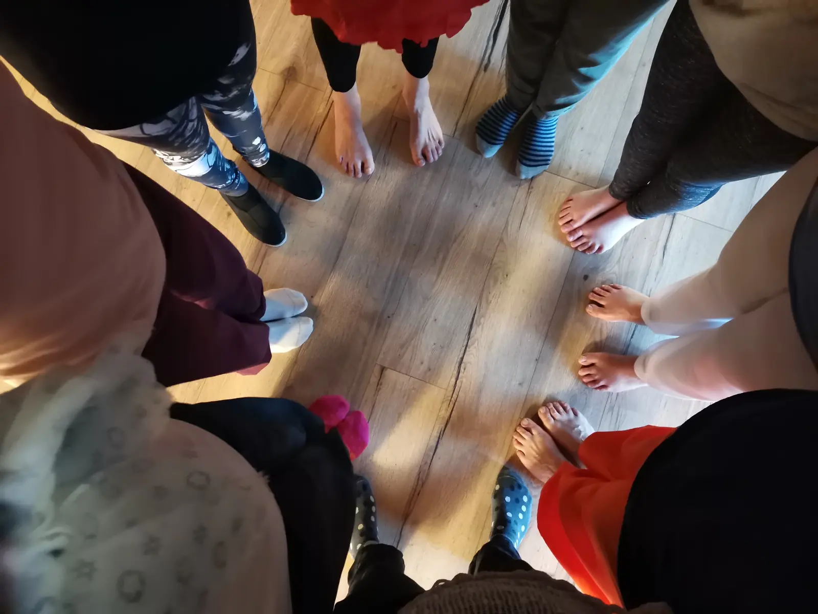 Des pieds nus disposés en cercle sur un parquet, vus d'en haut